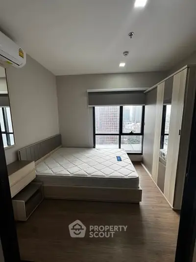 Modern bedroom with city view, featuring a comfortable bed and ample storage space.