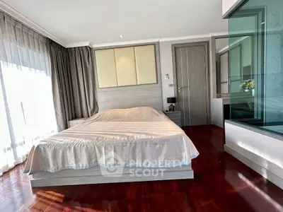 Spacious bedroom with hardwood floors and large windows in modern apartment.