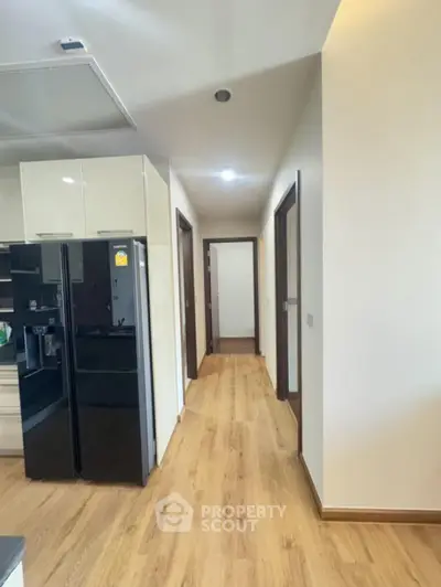 Modern hallway with wooden flooring and sleek kitchen appliances
