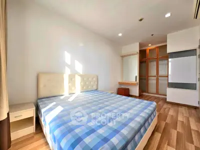 Spacious bedroom with stylish wooden flooring and ample natural light.
