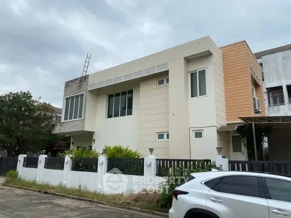 Modern two-story house with sleek design and large windows in a suburban neighborhood.