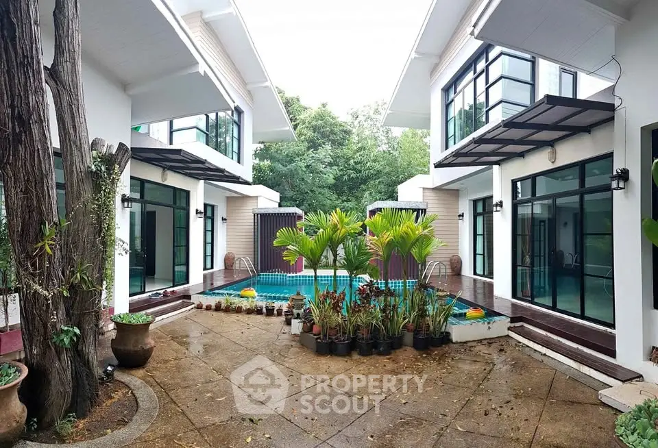 Modern villa with private pool and lush greenery, featuring large windows and contemporary design.
