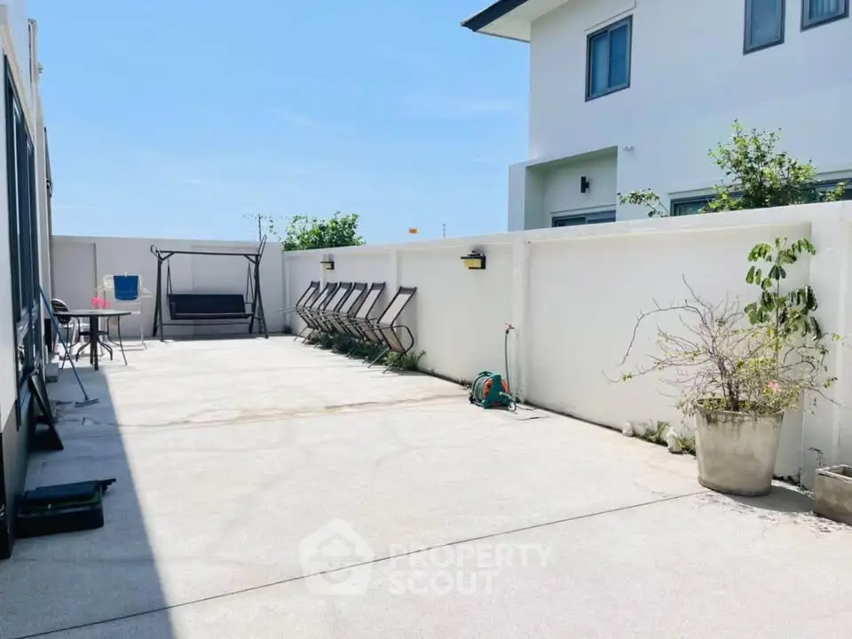 Spacious outdoor patio with seating and swing, perfect for relaxation and entertaining.