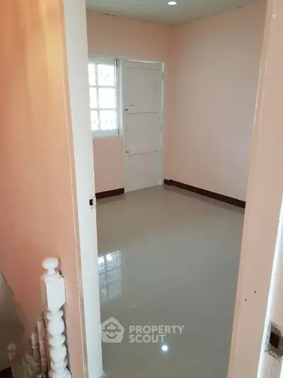 Cozy small room with glossy tiled floor and soft pink walls, perfect for a study or storage space.