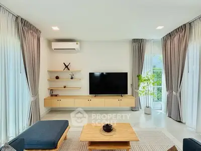 Modern living room with stylish decor, large TV, and natural light from floor-to-ceiling windows.