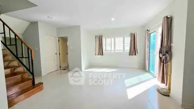 Spacious living room with natural light and modern staircase in a bright home.
