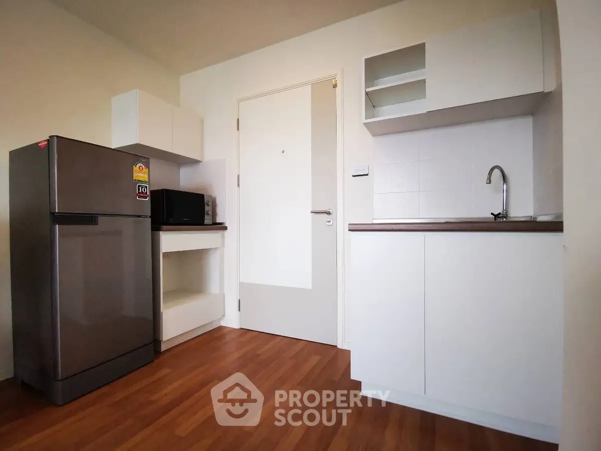 Modern kitchen with sleek cabinets and stainless steel fridge in a cozy apartment.
