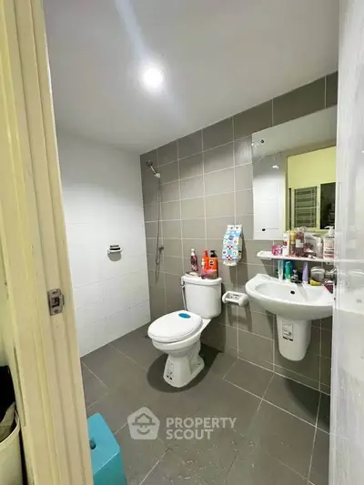 Modern bathroom with sleek tiles and essential fixtures in a contemporary home.