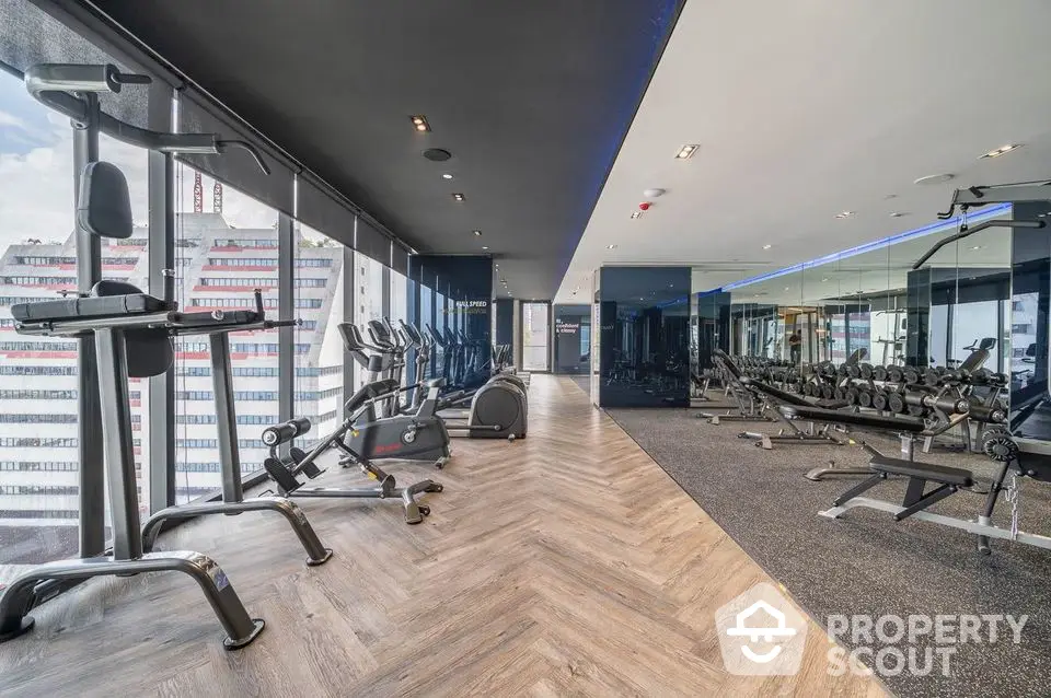 Modern gym with state-of-the-art equipment and panoramic city views in luxury building.