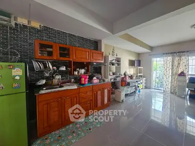 Spacious kitchen with wooden cabinets and open layout, featuring a green fridge and ample natural light.