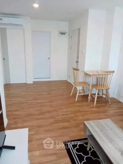 Modern living room with wooden flooring and minimalist furniture in a bright apartment.