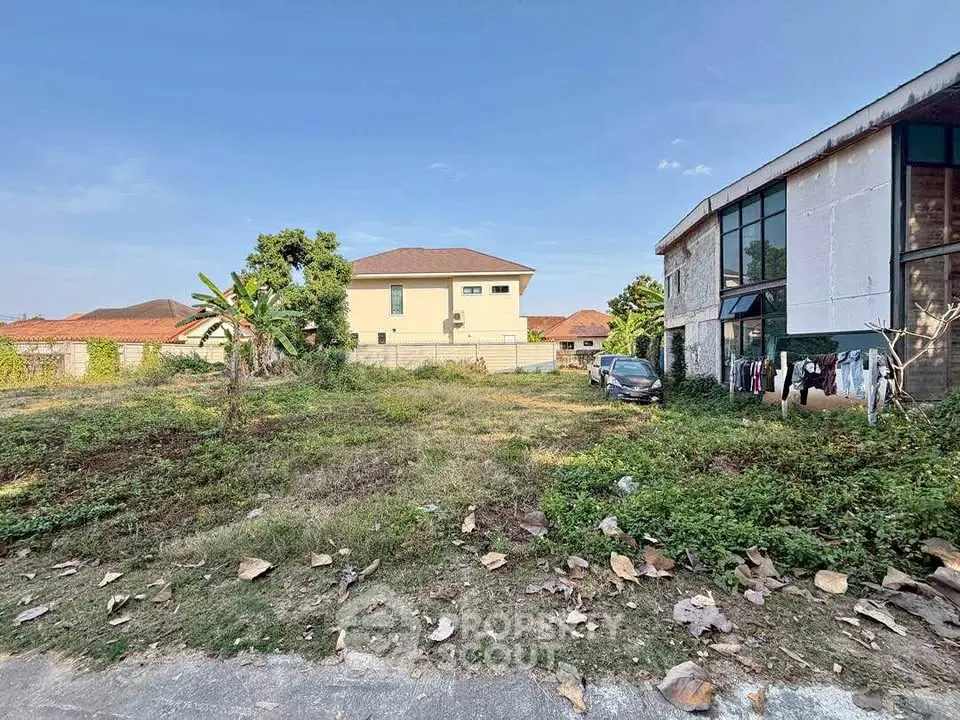 Spacious residential plot with potential for development, featuring a clear view of neighboring houses and lush greenery.