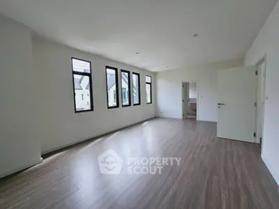 Spacious empty room with large windows and wooden flooring