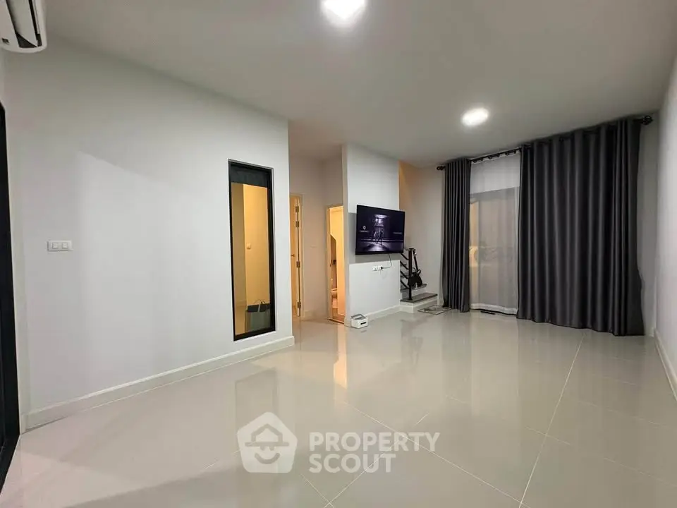 Spacious modern living room with sleek tile flooring and large windows for natural light.