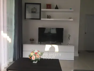 Modern living room with sleek TV stand, floating shelves, and elegant decor in natural light.