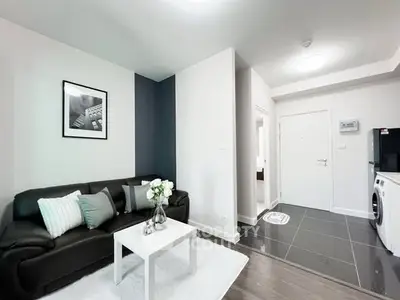 Modern living room with sleek black sofa and washing machine in stylish apartment