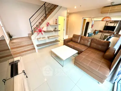 Modern living room with stylish staircase and cozy brown leather sofa