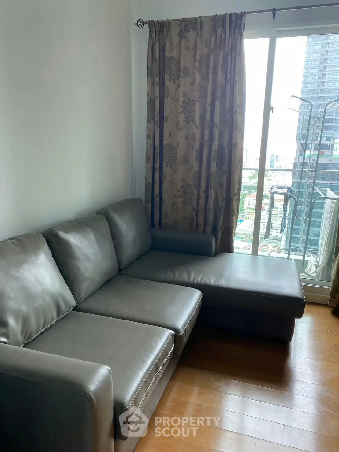 Modern living room with sleek leather sofa and city view from large window.