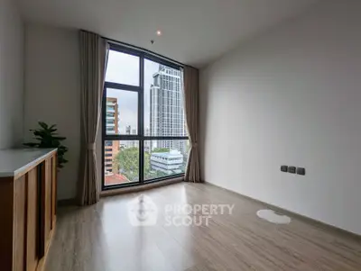 Spacious empty room with large window offering stunning city views, perfect for customization.