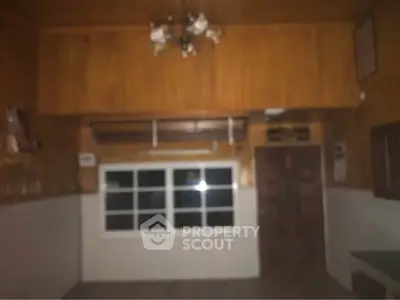 Dimly lit room with wooden walls and ceiling, featuring a window and a door.