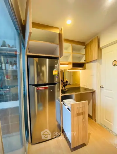 Modern compact kitchen with stainless steel fridge and wooden cabinets