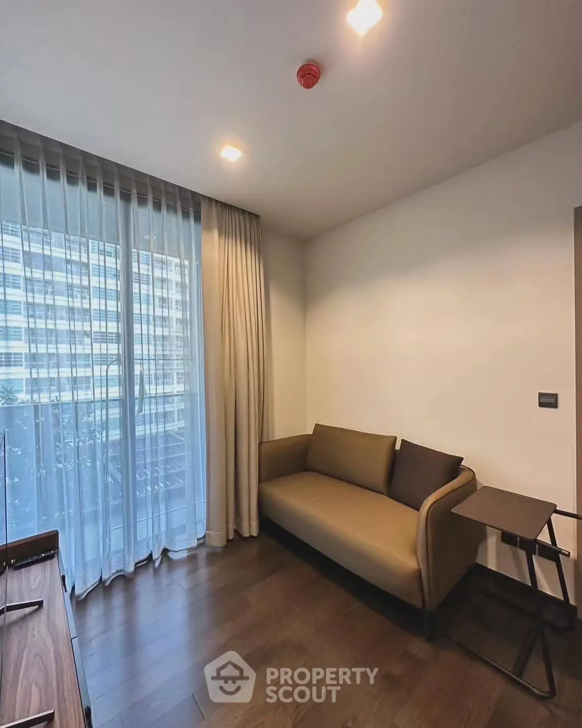 Modern living room with sleek sofa and floor-to-ceiling windows offering city views.