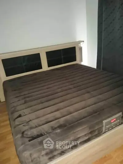 Cozy bedroom with plush bed and wooden flooring, perfect for relaxation.