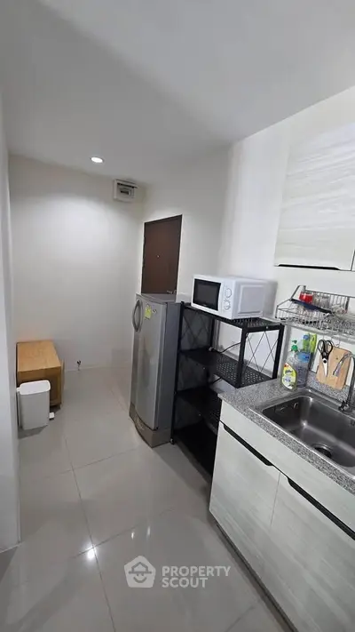 Modern kitchen with sleek appliances and minimalist design, featuring a microwave and refrigerator.
