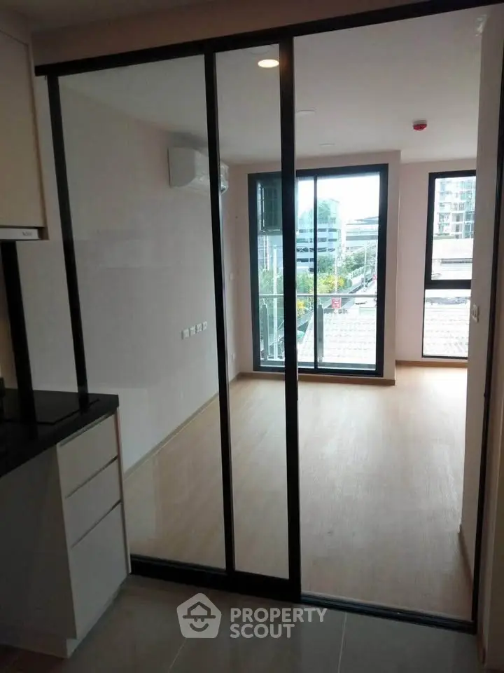 Modern apartment with sliding glass doors and balcony view, featuring sleek design and natural light.