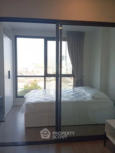 Modern bedroom with large window and city view, featuring sleek sliding glass doors and minimalist design.
