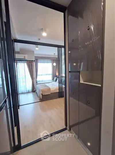 Modern apartment entrance leading to a cozy bedroom with large windows and stylish decor.