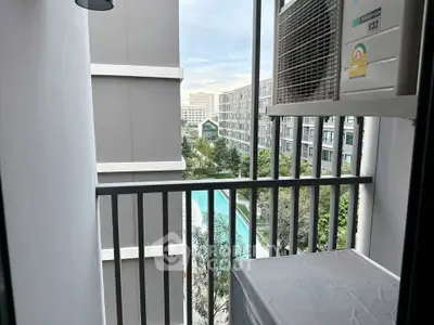 Charming balcony view overlooking modern apartment complex with pool and lush greenery.