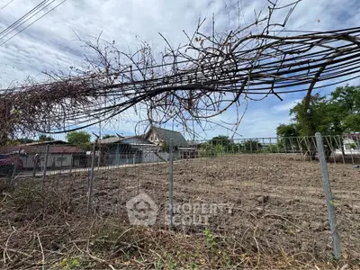Vacant land with potential for development in a residential neighborhood, featuring a clear sky and surrounding greenery.