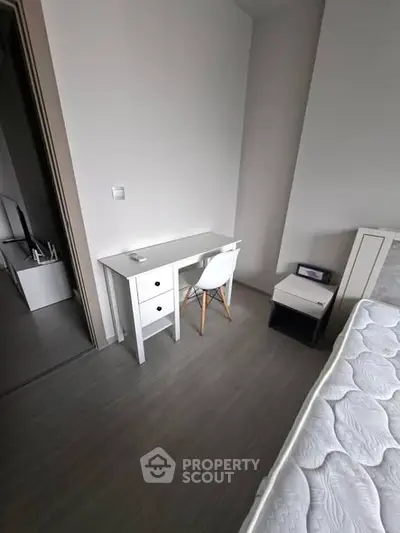 Modern bedroom with minimalist desk and chair, featuring sleek flooring and neutral tones.