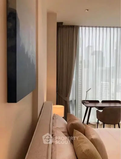 Modern bedroom with city view, featuring elegant decor and a stylish work desk by the window.