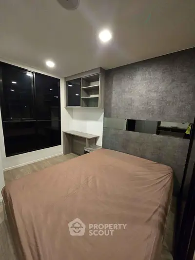 Modern bedroom with sleek design and large windows in a contemporary apartment.