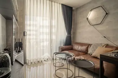 Modern living room with leather sofa and stylish decor, featuring floor-to-ceiling windows and elegant curtains.