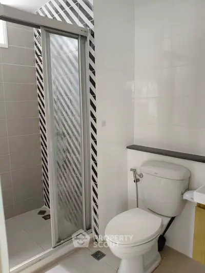 Modern bathroom with sleek shower and toilet in contemporary design.