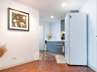 Modern kitchen with sleek cabinetry and large refrigerator in stylish apartment.