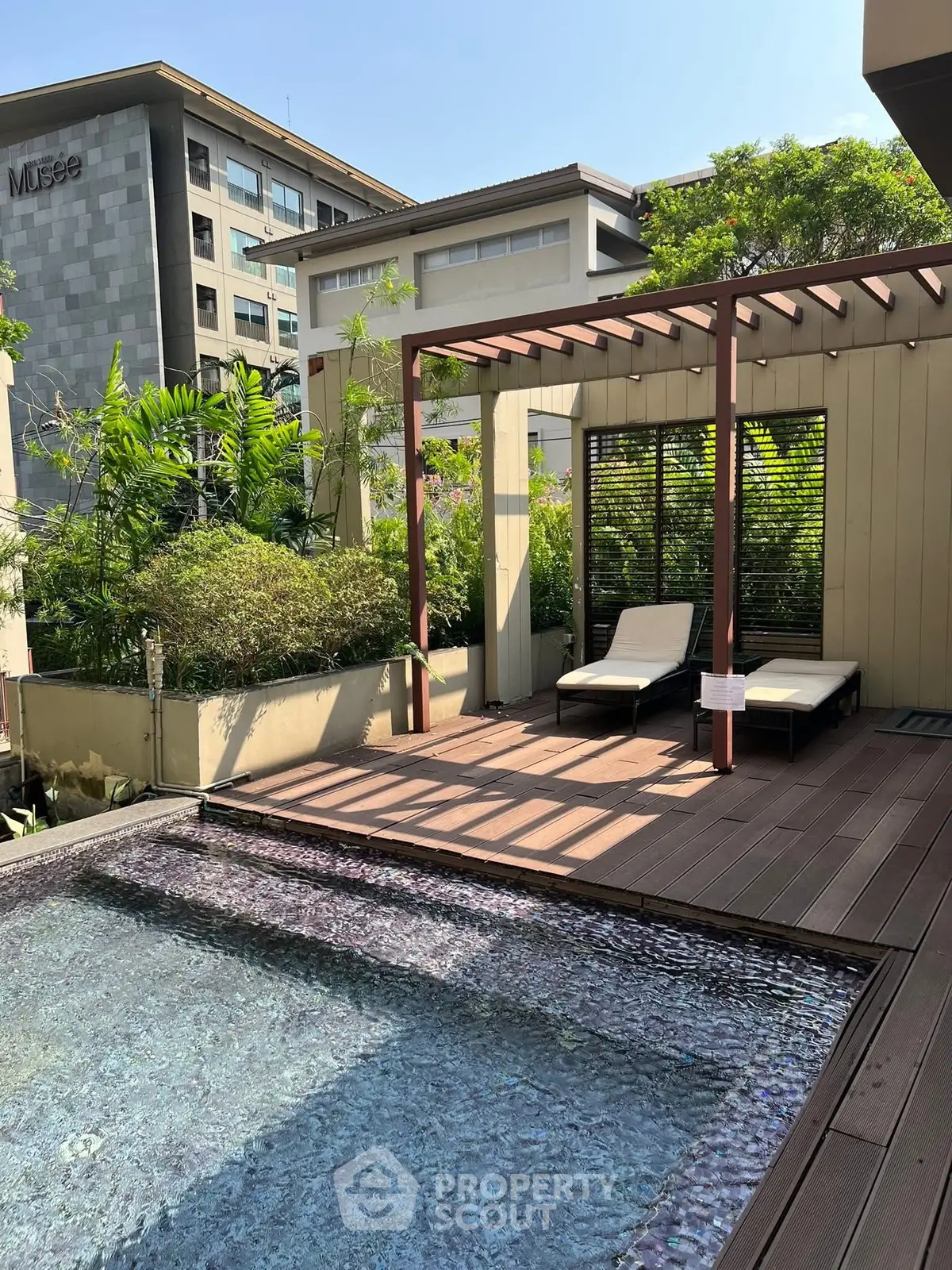 Luxurious rooftop pool with stylish deck and lush greenery, perfect for relaxation and leisure.