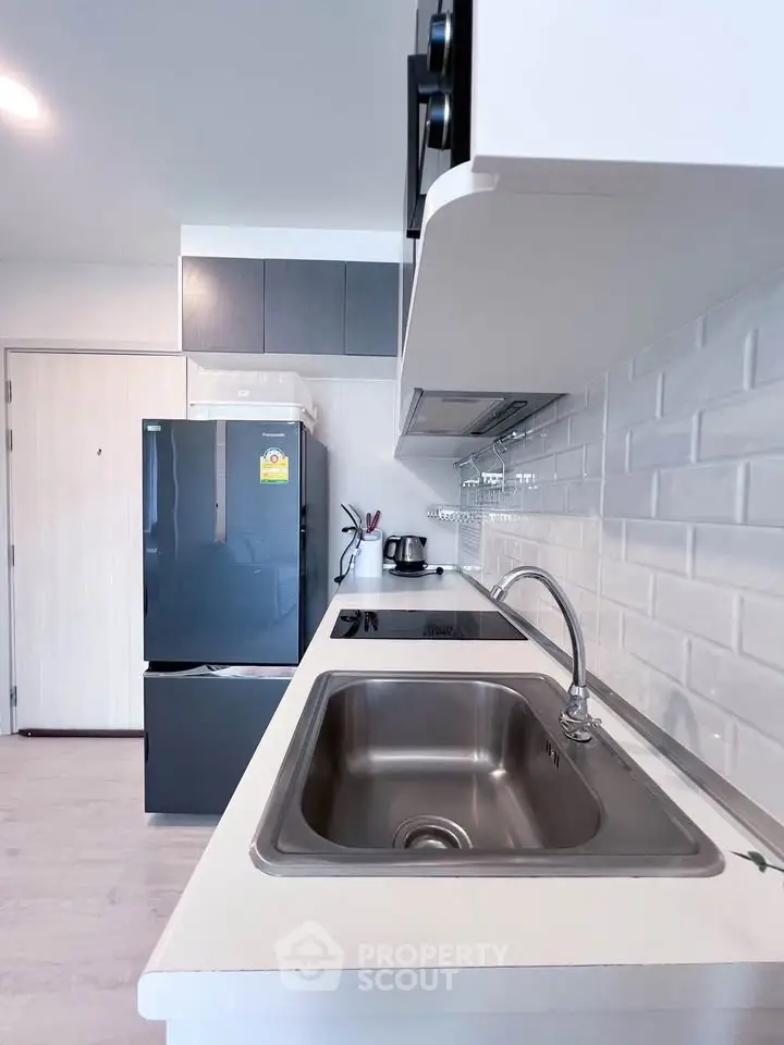 Modern kitchen with sleek appliances and stylish backsplash in a contemporary apartment.