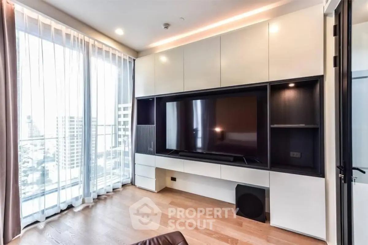 Modern living room with large TV and floor-to-ceiling windows offering city views.