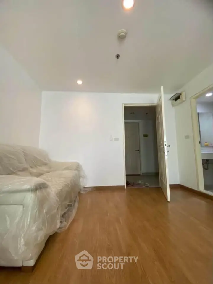 Spacious living room with wooden flooring and covered sofa in modern apartment.