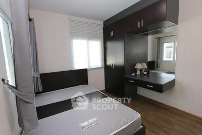 Modern bedroom with sleek dark wood furniture and large window for natural light.