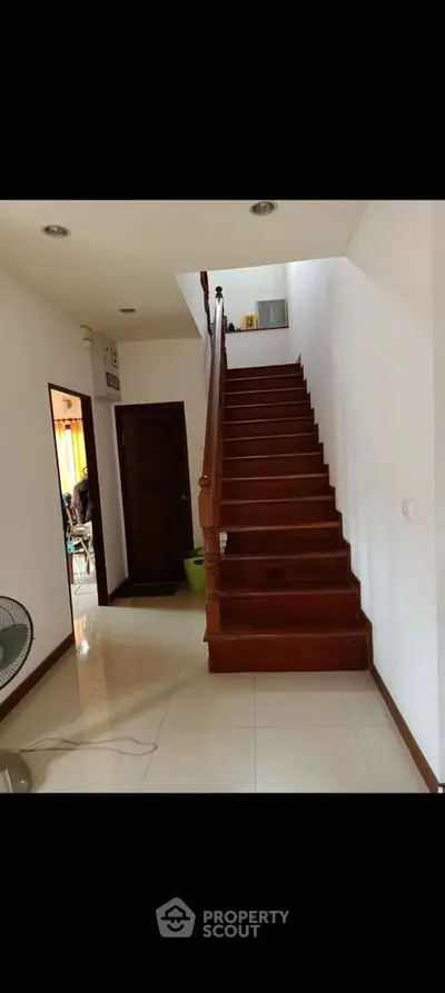 Elegant wooden staircase in modern home interior with polished tile flooring.