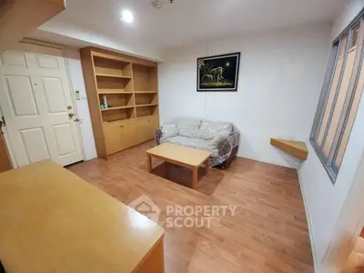 Cozy living room with wooden flooring and built-in shelves, perfect for relaxation.