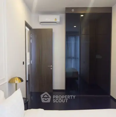 Modern bedroom with sleek black wardrobe and air conditioning unit
