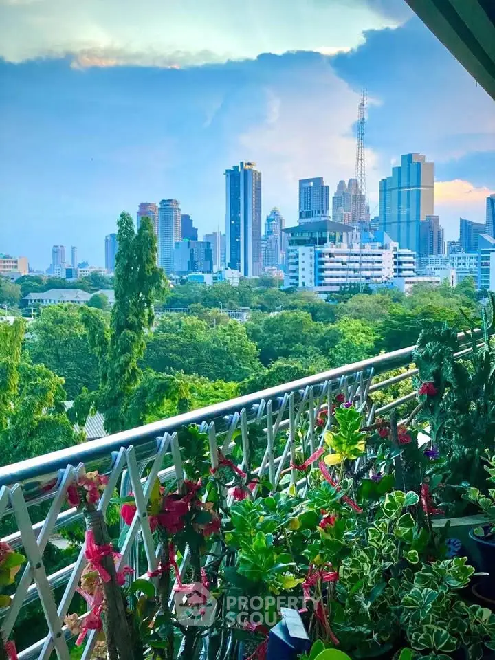 Stunning cityscape view from a lush balcony with vibrant greenery and skyline backdrop.
