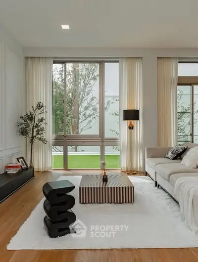 Elegant living room with modern decor and large windows overlooking greenery.