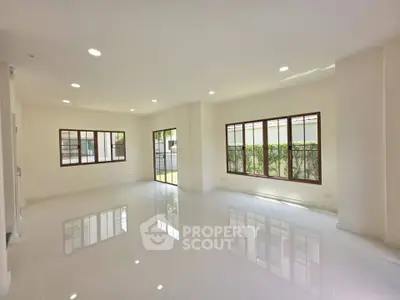 Spacious and bright living room with large windows and glossy floors, perfect for modern living.